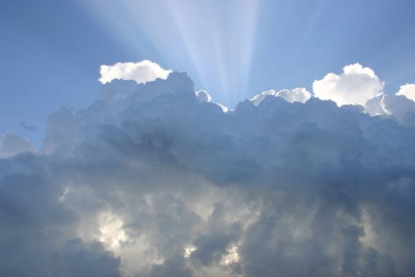 Sonne strahlt hinter den Wolken hervor bei blauem Himmel